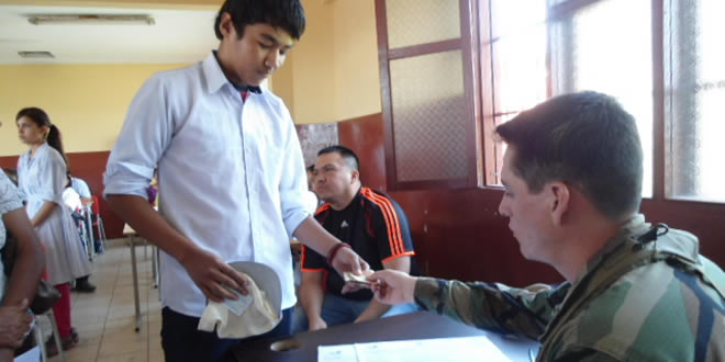 Un efectivo de las FFAA realizan el pago del Bono Juancito Pinto a un estudiante.