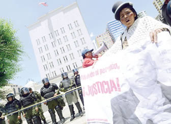 Una mujer frente a la embajada de EEUU muestra afiche con rostro de Sanchez de Lozada y el pedido de justicia