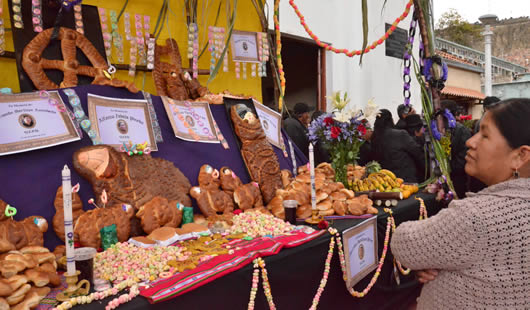 Todos santos en Bolivia: una mujer eleva oraciones frente a una mesa instalada en el Cementerio.