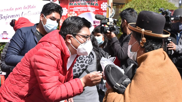 El concejal de El Alto, Javier Tarqui, entrega pantuflas a una adulto mayor.